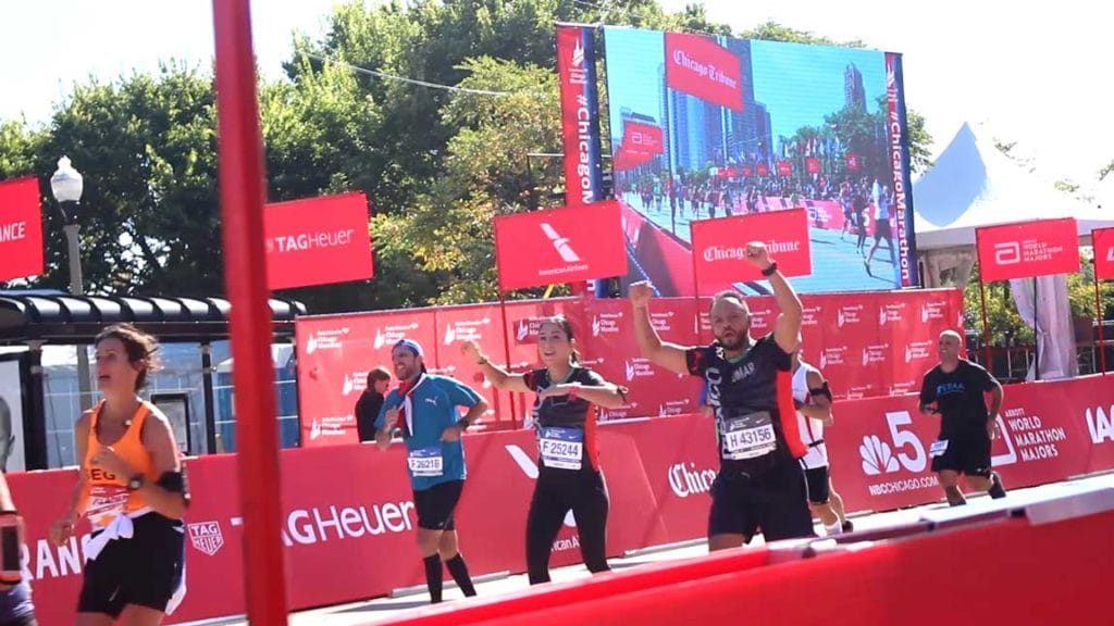 runners cross the finish line by a large led screen