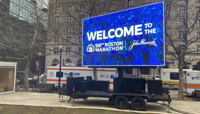 max mobile led screen trailer at the boston marathon. the screen is displaying text that reads: "welcome to the 126th boston marathon john hancock"